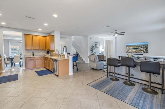 kitchen featuring light tile patterned flooring, dishwasher, backsplash, kitchen peninsula, and a breakfast bar