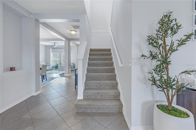 stairway featuring tile patterned floors, baseboards, a ceiling fan, and visible vents