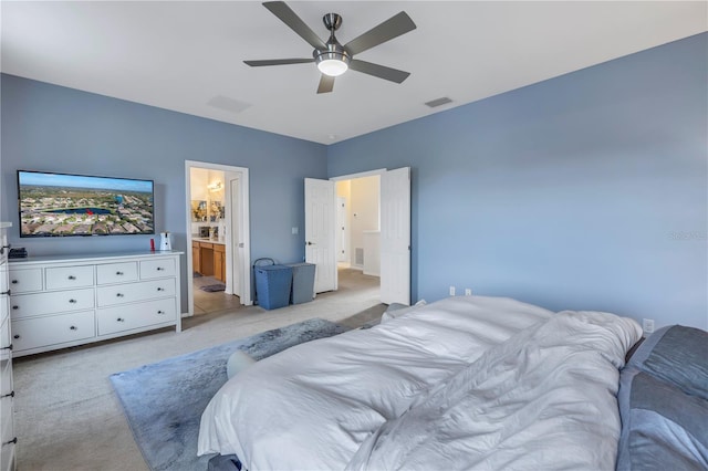 bedroom with connected bathroom, light colored carpet, and ceiling fan