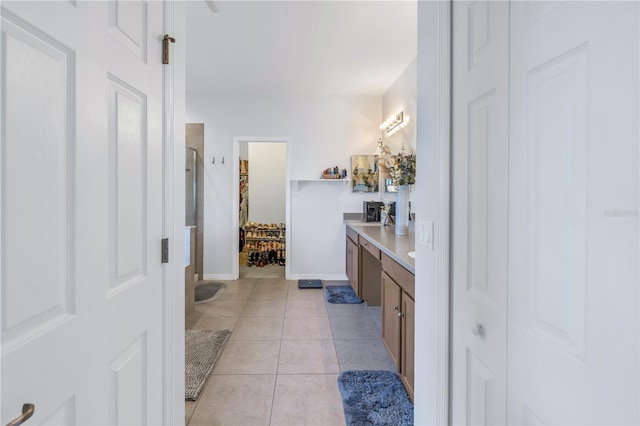 bathroom featuring double vanity, a shower with shower door, tile patterned floors, baseboards, and a closet