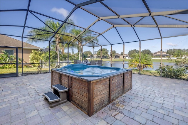 view of patio with a water view, a hot tub, and glass enclosure