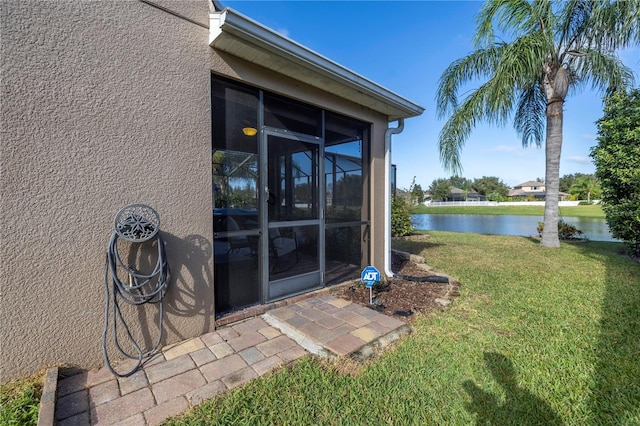 property entrance with a water view, a yard, and stucco siding