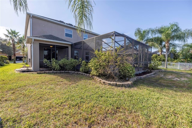 back of property featuring a lawn, fence, glass enclosure, and stucco siding