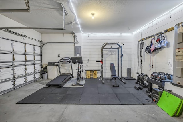 workout area with concrete block wall, electric panel, a textured ceiling, and a garage