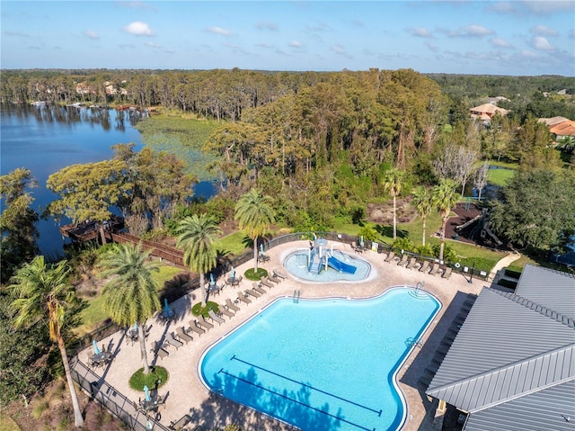 community pool featuring a patio, a water view, and a view of trees