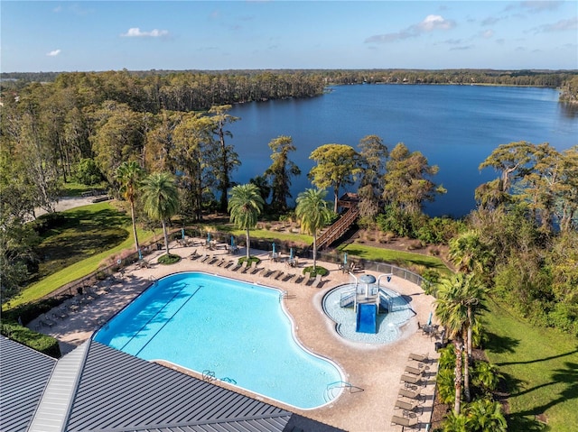 community pool featuring a patio, a water view, and a wooded view