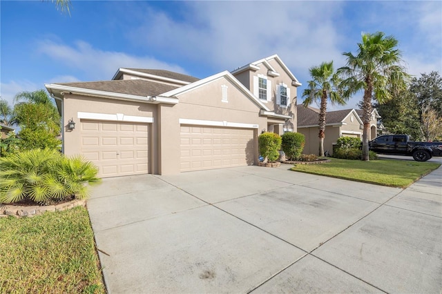 traditional-style home with an attached garage, stucco siding, driveway, and a front yard