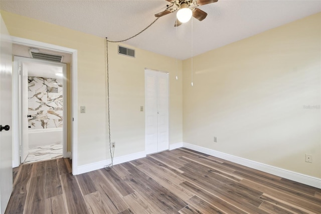 unfurnished bedroom featuring dark hardwood / wood-style flooring, a textured ceiling, a closet, and ceiling fan