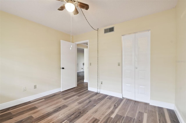 unfurnished bedroom with a closet, a textured ceiling, hardwood / wood-style flooring, and ceiling fan