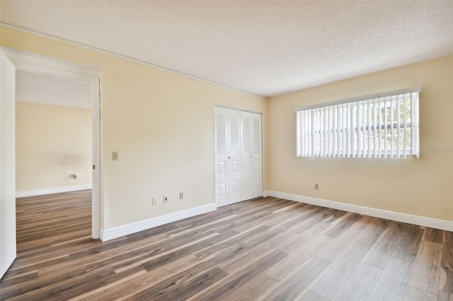 unfurnished bedroom featuring a closet, a textured ceiling, and hardwood / wood-style floors