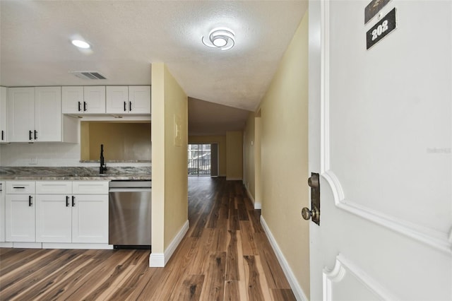 kitchen with stone counters, a textured ceiling, dark hardwood / wood-style flooring, stainless steel dishwasher, and white cabinets