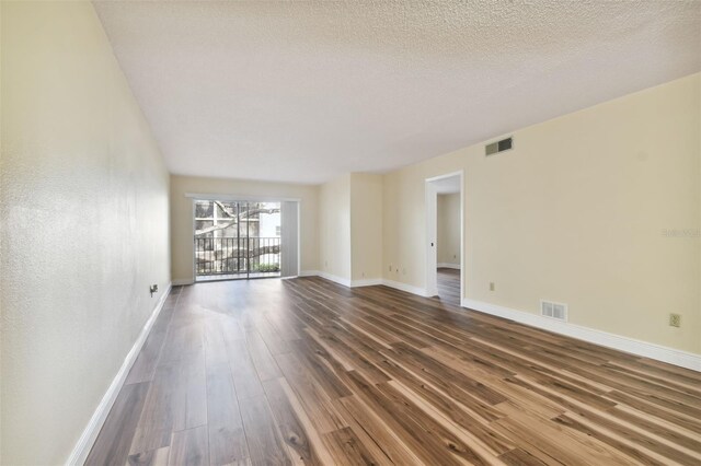 spare room featuring a textured ceiling and dark hardwood / wood-style floors