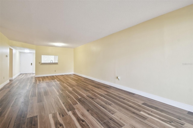 spare room featuring a textured ceiling and dark hardwood / wood-style flooring