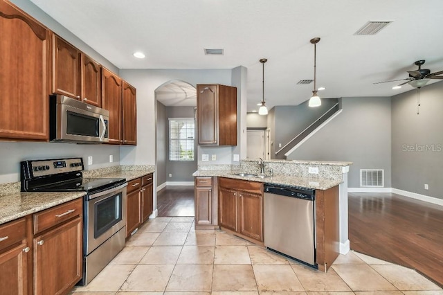 kitchen featuring ceiling fan, sink, stainless steel appliances, light hardwood / wood-style flooring, and pendant lighting