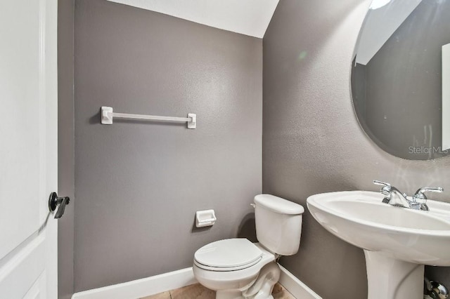 bathroom with tile patterned flooring, vaulted ceiling, toilet, and sink