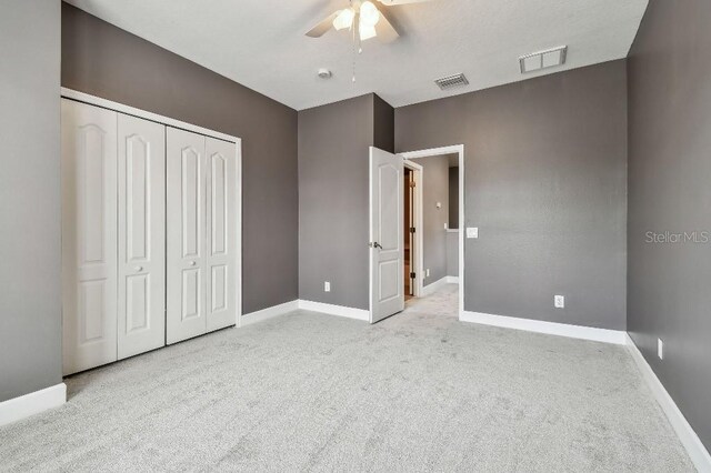 unfurnished bedroom with light colored carpet, a closet, and ceiling fan