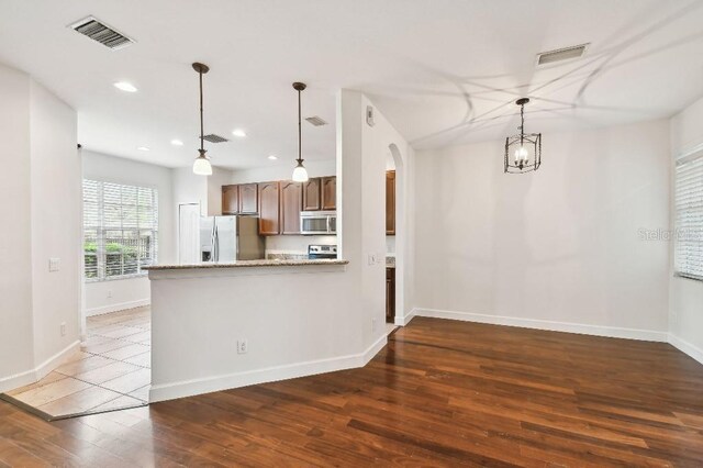 kitchen featuring visible vents, stainless steel appliances, arched walkways, and decorative light fixtures