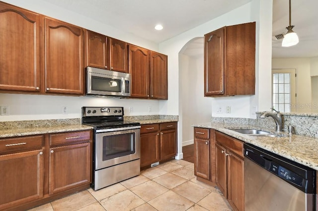 kitchen featuring visible vents, appliances with stainless steel finishes, light stone counters, pendant lighting, and a sink