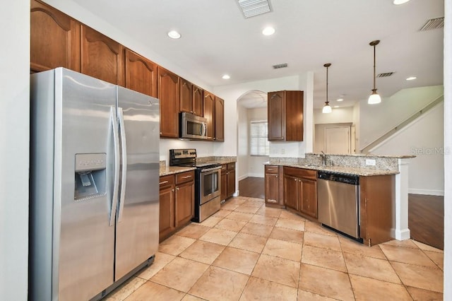 kitchen featuring appliances with stainless steel finishes, decorative light fixtures, visible vents, and light stone counters