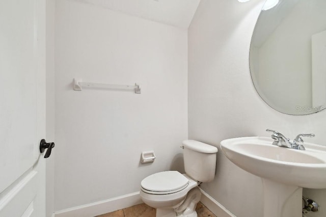 half bath featuring baseboards, a sink, toilet, and tile patterned floors