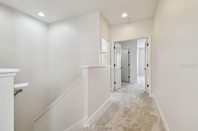 hallway with recessed lighting, baseboards, light colored carpet, and an upstairs landing