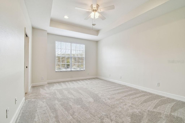 spare room with baseboards, light colored carpet, ceiling fan, a tray ceiling, and recessed lighting