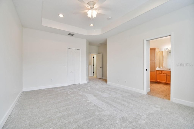 unfurnished bedroom with recessed lighting, light carpet, visible vents, baseboards, and a tray ceiling