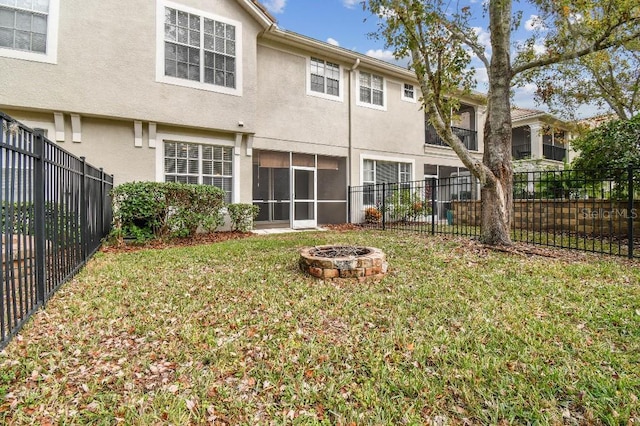 rear view of house with an outdoor fire pit, a fenced backyard, and stucco siding