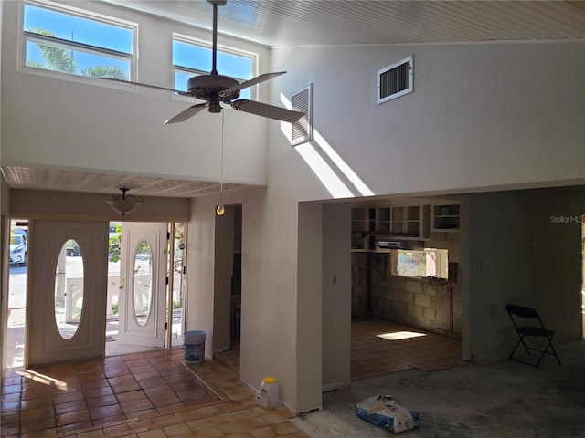 foyer with a towering ceiling, a wealth of natural light, and ceiling fan