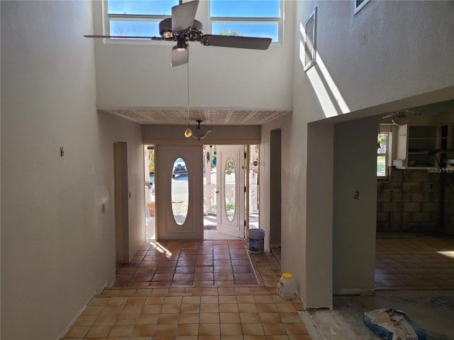 entrance foyer featuring ceiling fan, tile patterned flooring, and a high ceiling