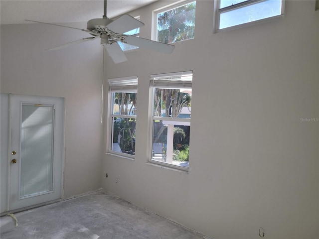 spare room featuring ceiling fan, a healthy amount of sunlight, and a high ceiling