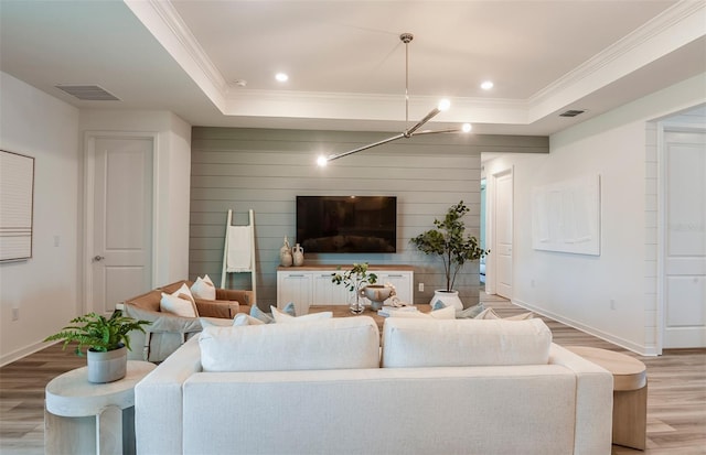 living room featuring hardwood / wood-style flooring, a raised ceiling, and crown molding