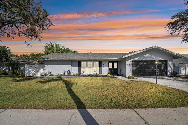 view of front of property featuring a garage, brick siding, fence, driveway, and a lawn