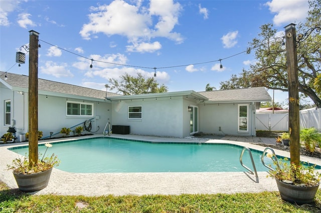 rear view of property featuring a fenced in pool