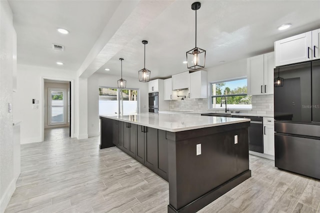 kitchen featuring black fridge, white cabinetry, a kitchen island, and light hardwood / wood-style floors