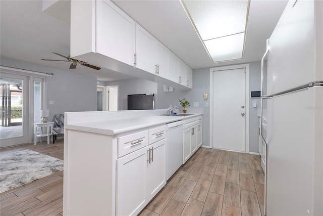 kitchen with ceiling fan, kitchen peninsula, sink, white appliances, and white cabinets