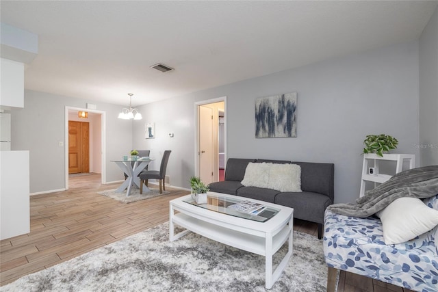 living room with light wood-type flooring and a chandelier