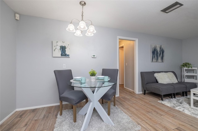 dining space with light hardwood / wood-style flooring and a notable chandelier