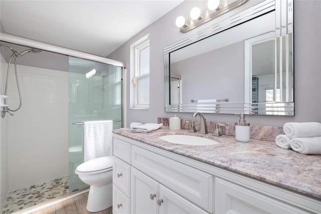 bathroom with toilet, vanity, a shower with shower door, and hardwood / wood-style flooring