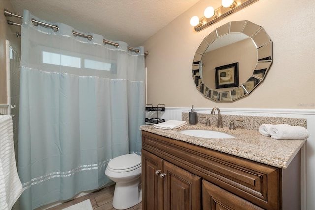 bathroom with toilet, a textured ceiling, and vanity