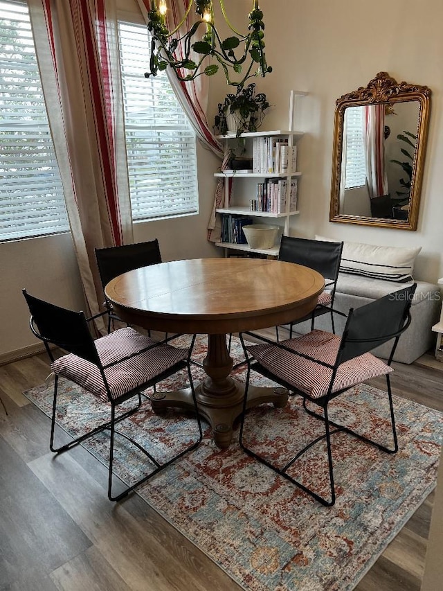 dining space with hardwood / wood-style floors and a notable chandelier