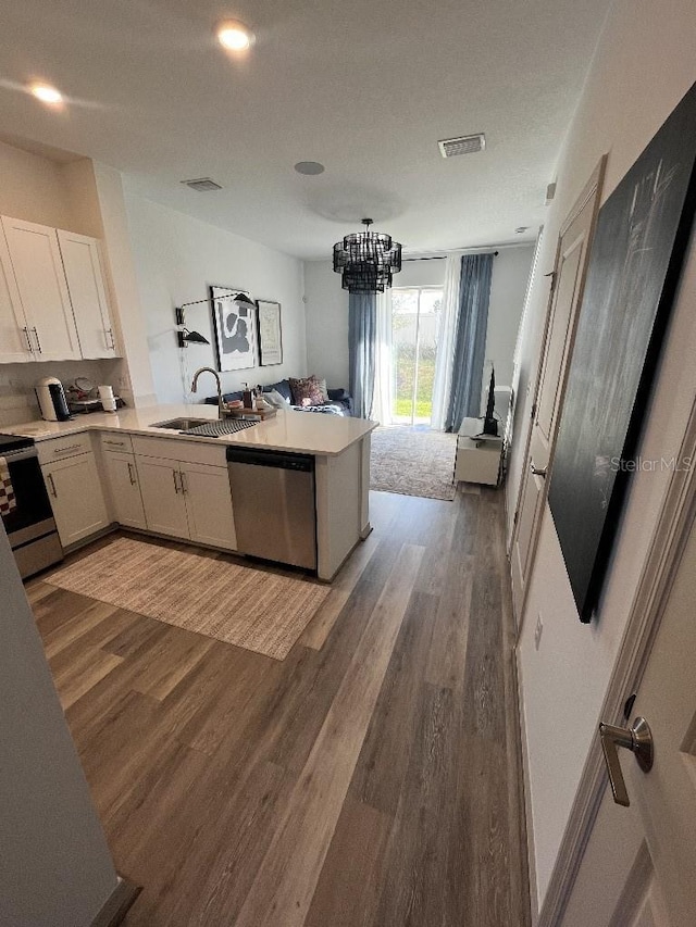 kitchen featuring kitchen peninsula, sink, appliances with stainless steel finishes, wood-type flooring, and a chandelier