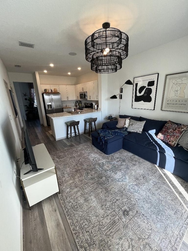 living room with a chandelier, sink, and dark wood-type flooring