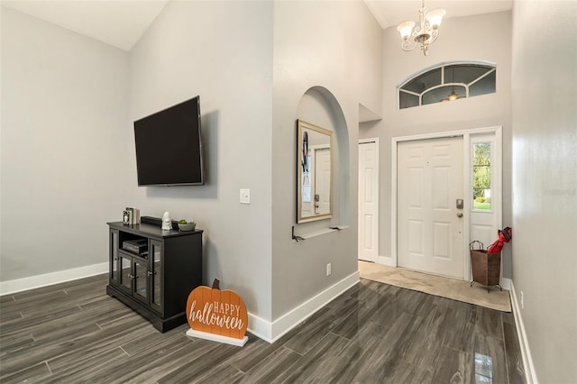 foyer entrance with an inviting chandelier, high vaulted ceiling, and dark hardwood / wood-style flooring