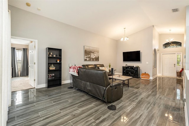 living room with dark wood-type flooring, a notable chandelier, and lofted ceiling