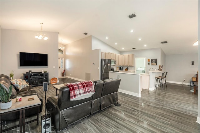 living room featuring an inviting chandelier, lofted ceiling, and dark wood-type flooring