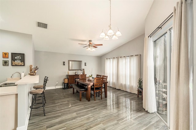 dining space featuring dark wood-type flooring, vaulted ceiling, plenty of natural light, and ceiling fan with notable chandelier