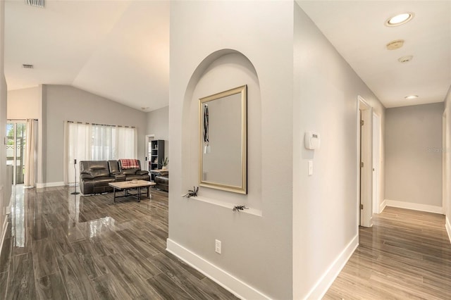 corridor with hardwood / wood-style flooring and vaulted ceiling