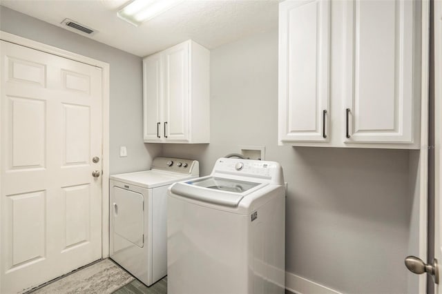 laundry room with cabinets, hardwood / wood-style floors, a textured ceiling, and washer and clothes dryer