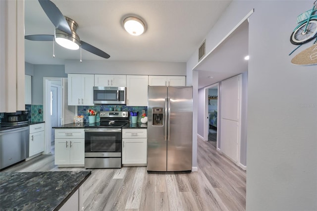 kitchen with backsplash, dark stone countertops, white cabinetry, appliances with stainless steel finishes, and light hardwood / wood-style floors